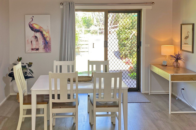 Roomy dining area with white table and chairs adjoining the kitchen in an open-plan style
